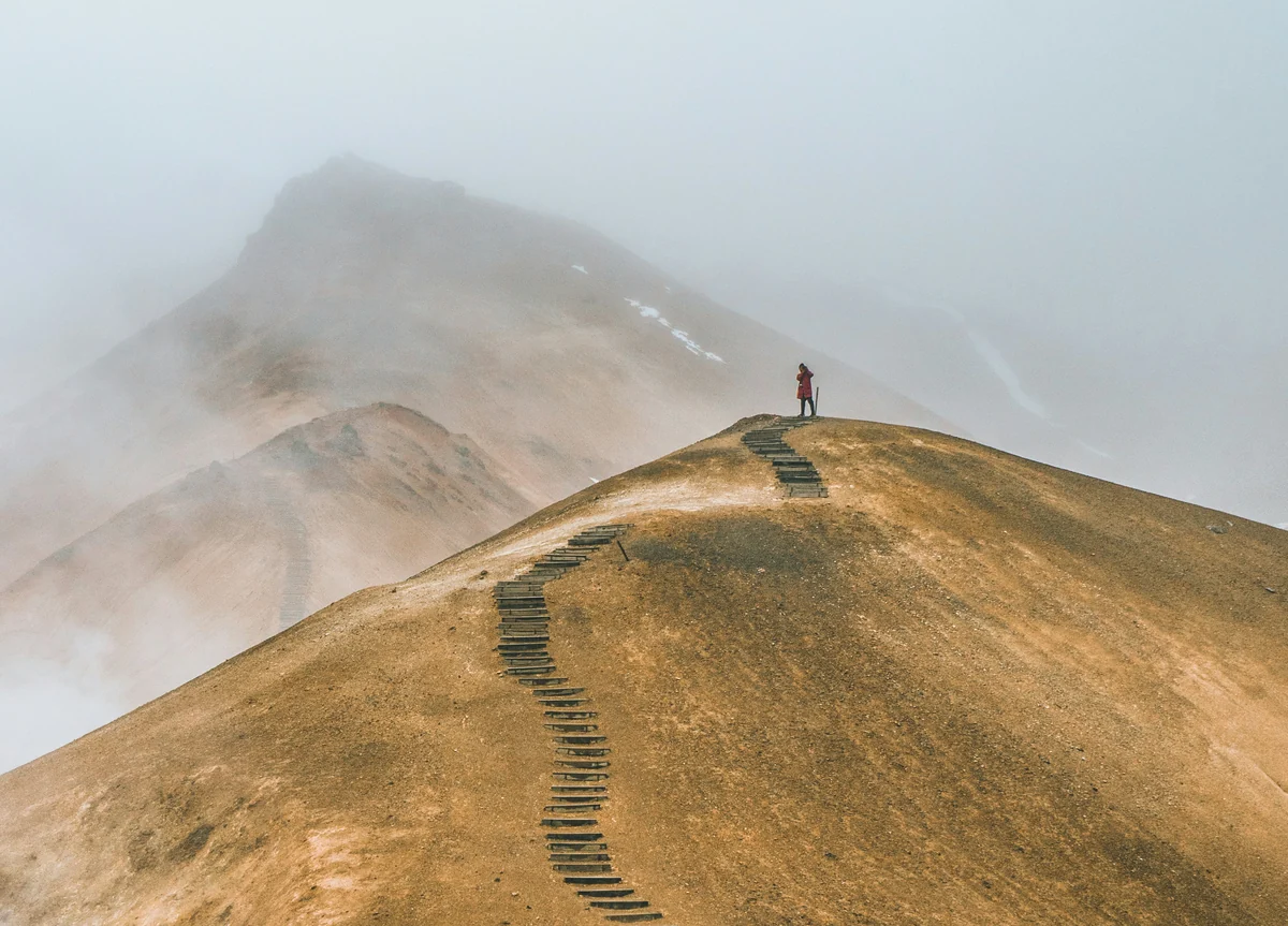 Persona in cima a una collina con un sentiero a gradoni che sale serpeggiando, metafora dell'apprendimento come percorso non lineare